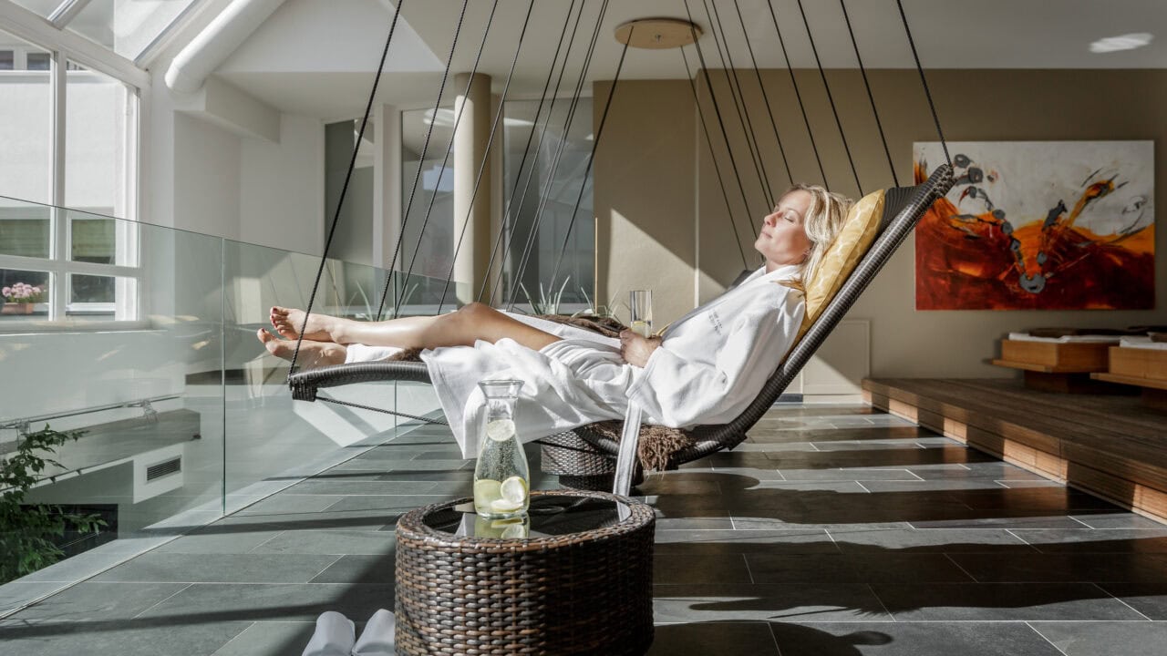 Frau entspannt auf Hängesessel mit Getränk im Spa