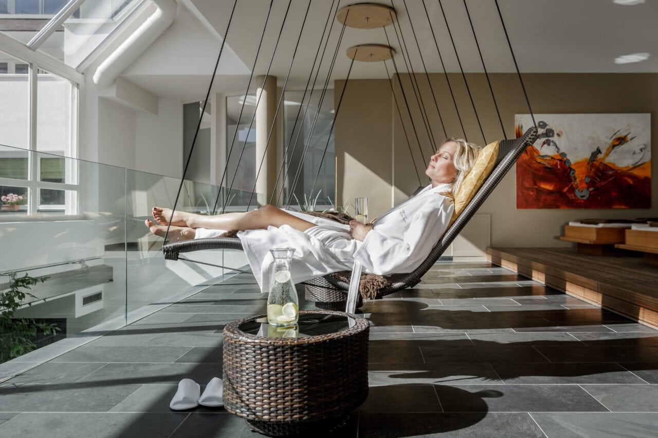 Frau entspannt auf Hängesessel mit Getränk im Spa