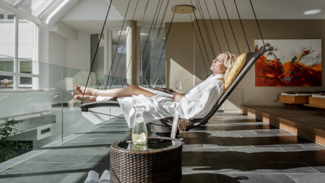 Frau entspannt auf Hängesessel mit Getränk im Spa
