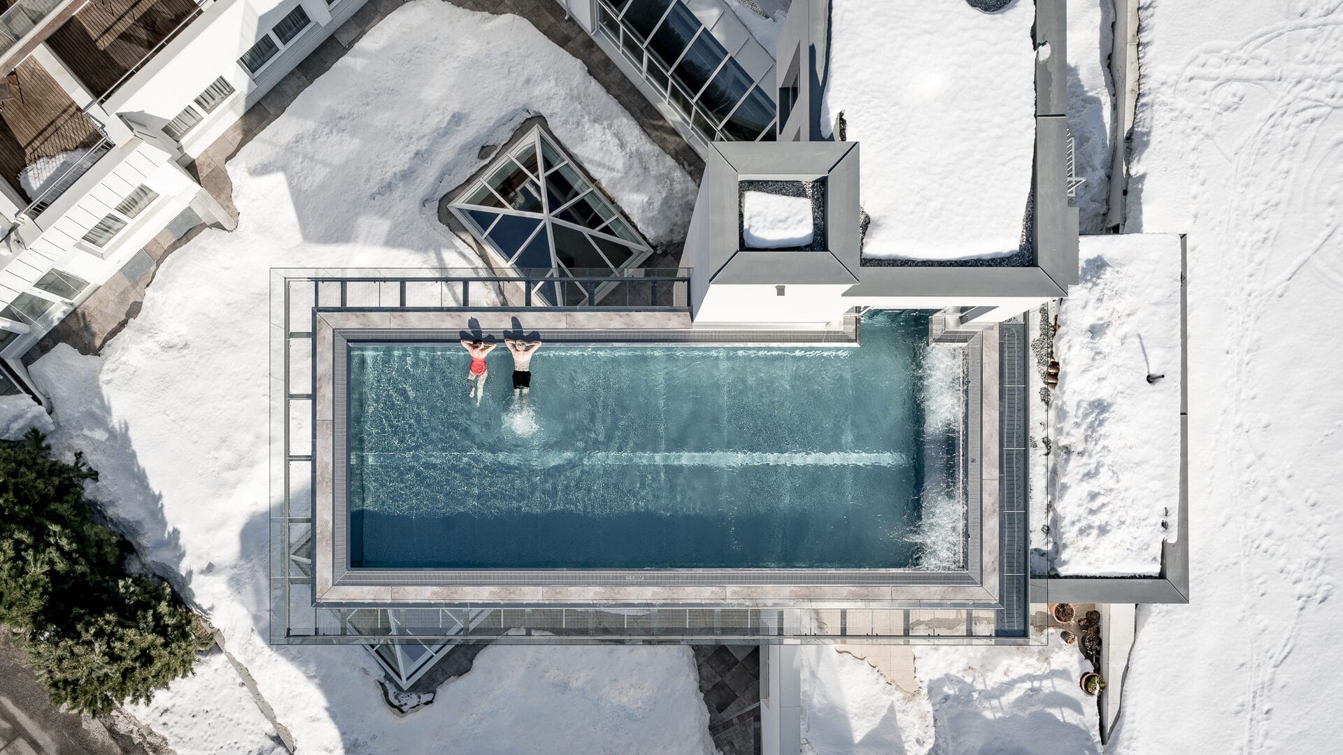 Dachpool im Schnee mit zwei schwimmenden Personen