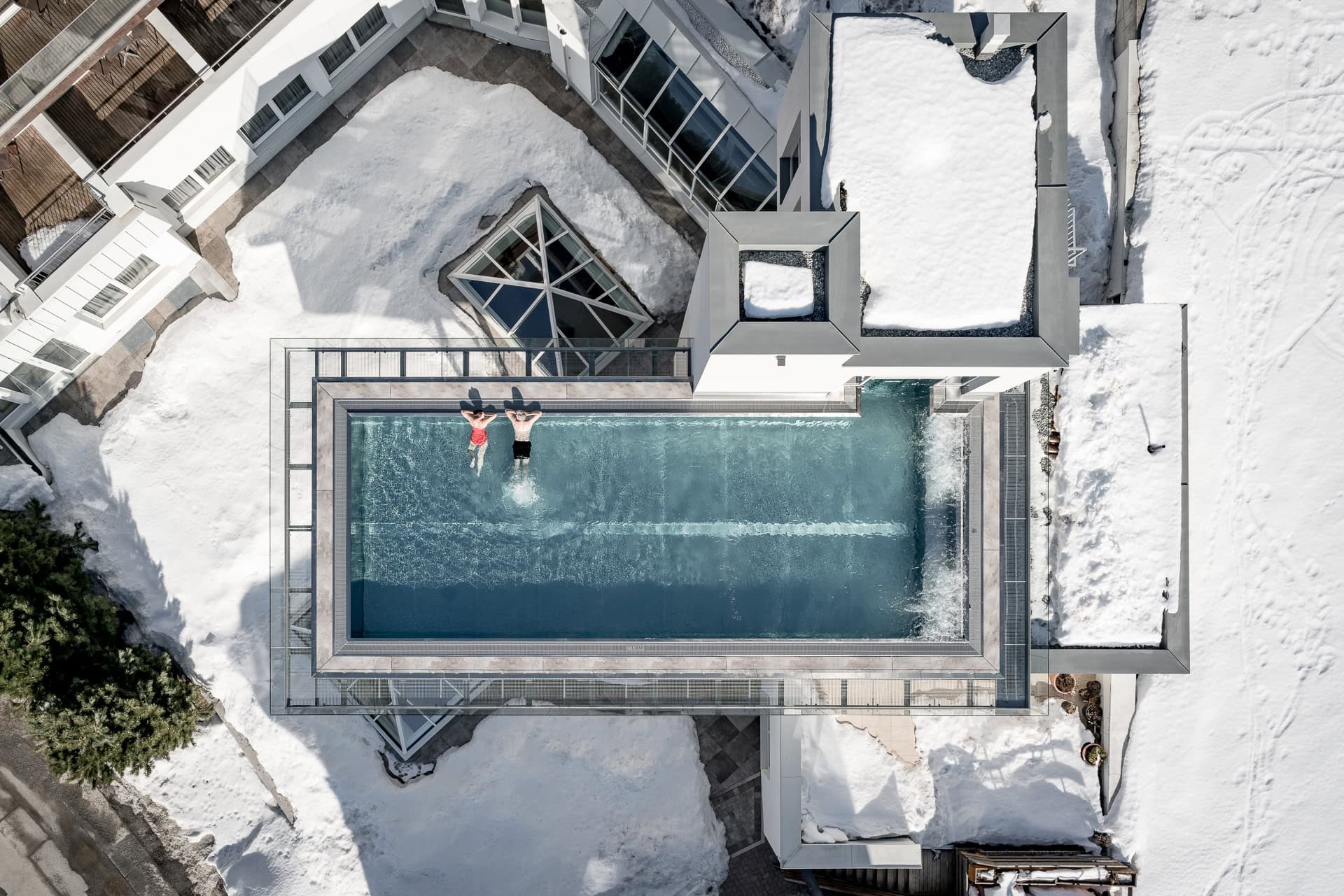 Dachpool im Schnee mit zwei schwimmenden Personen