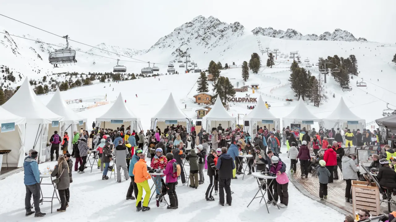 Menschen in Skigebiet mit weißen Pavillons und Bergen