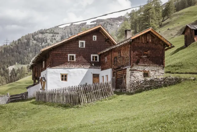 Alpenhaus mit Holzzaun in grüner Berglandschaft