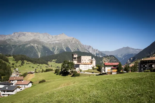 Burg in idyllischer Berglandschaft mit blauen Himmel.