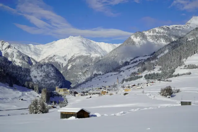 Verschneite Alpenlandschaft mit Dorf und Bergen.