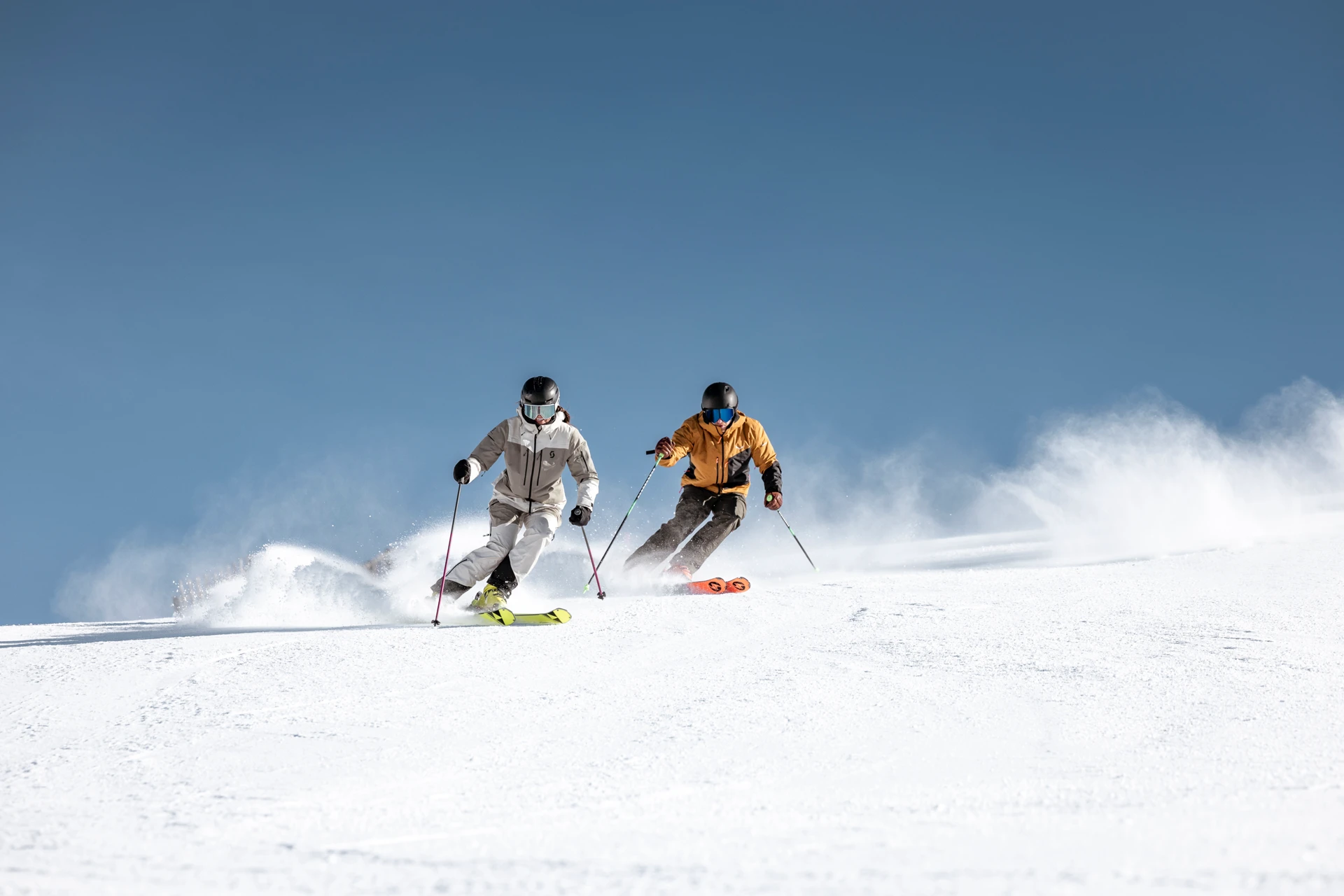 Zwei Skifahrer rasen einen schneebedeckten Hang hinunter.