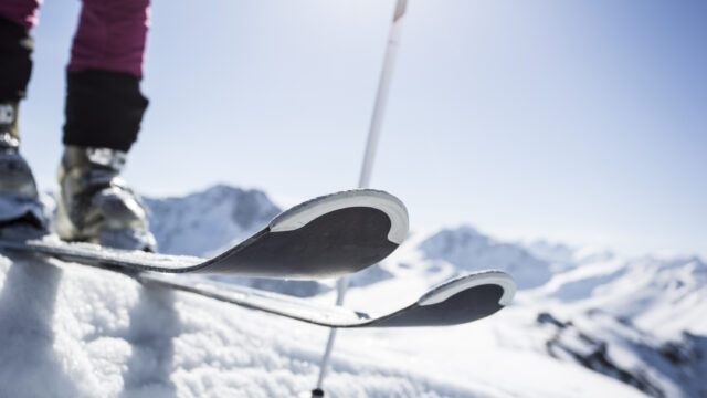 Skifahrer auf verschneitem Berg mit blauem Himmel