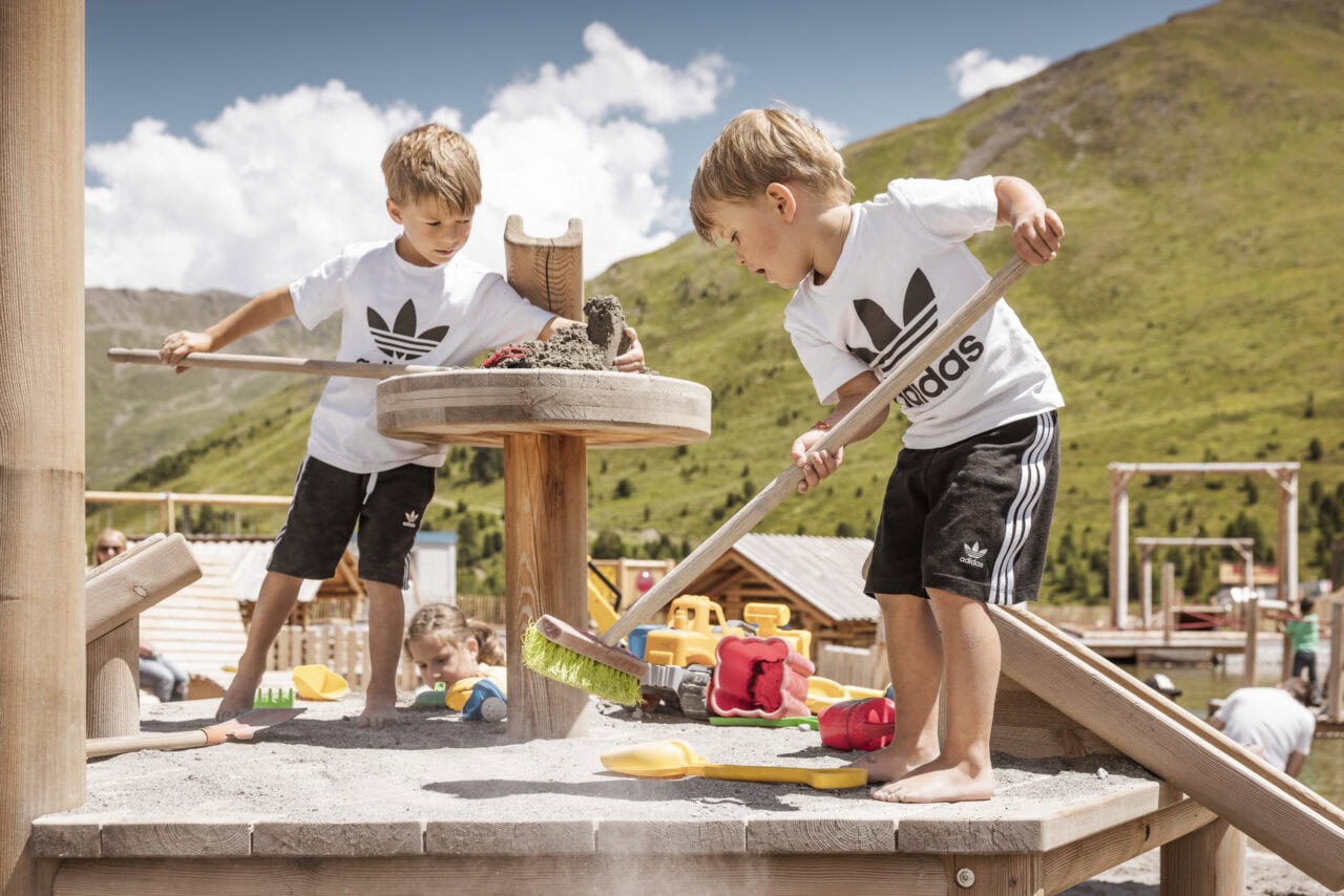 Zwei Kinder spielen im Sand auf Spielplatz.