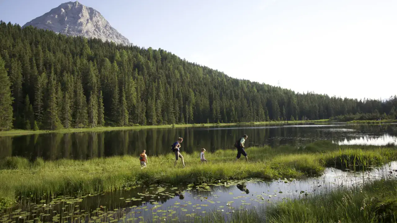 Familie wandert am See vor Berglandschaft.