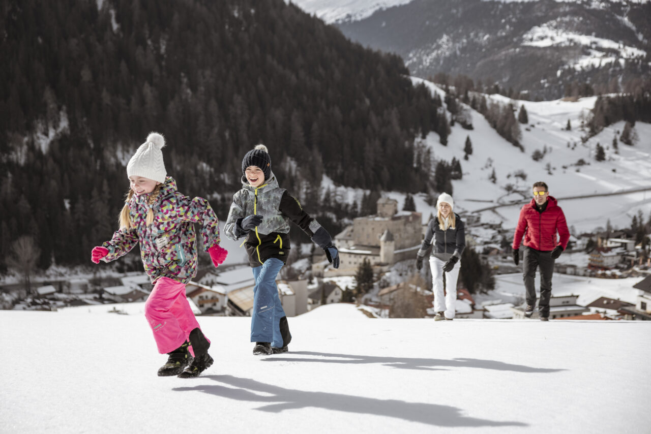 Familie läuft im Schnee vor Berglandschaft