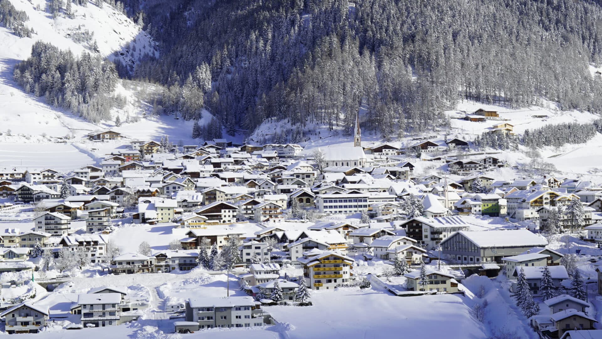 Verschneites Dorf in den Alpen mit Kirche.