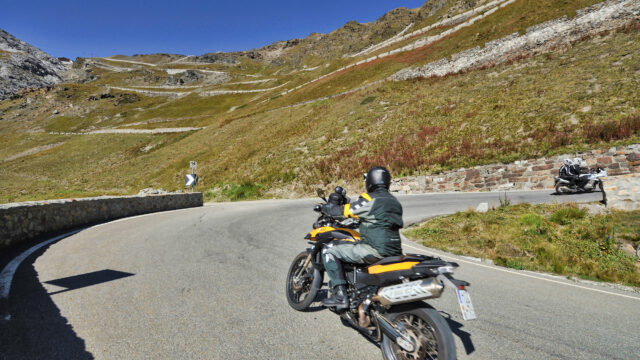 Motorradfahrer auf kurviger Bergstraße bei klarem Himmel