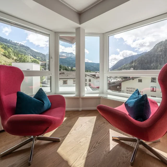 Zwei rote Sessel mit Bergblick durch Fenster.