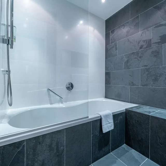 Modernes Badezimmer mit Badewanne und grauen Fliesen